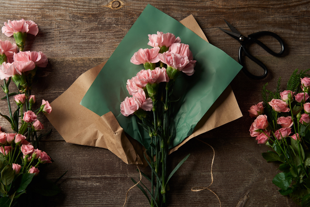 felülnézet gyönyörű rózsaszín virágok, kézműves papír és olló, fa felületre  - Fotó, kép