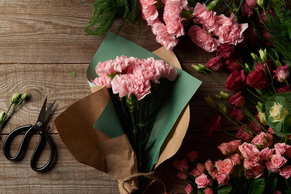 Draufsicht auf schöne zarte Blumen mit Bastelpapier und Schere auf Holzoberfläche  - Foto, Bild