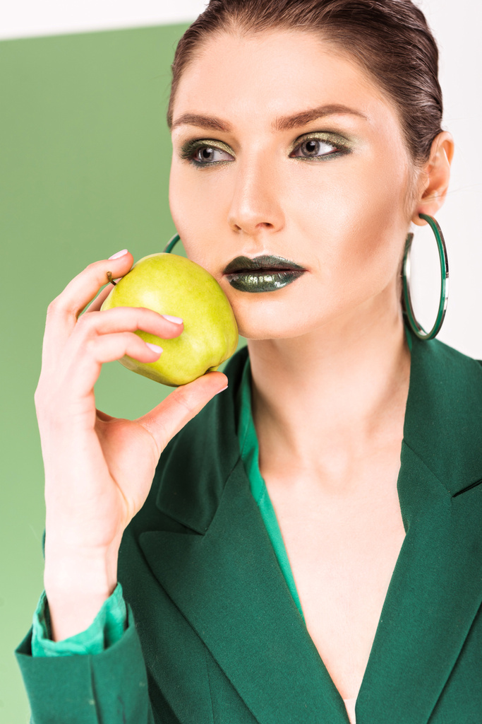 selective focus of beautiful stylish woman holding apple and posing with sea green on background - Photo, Image