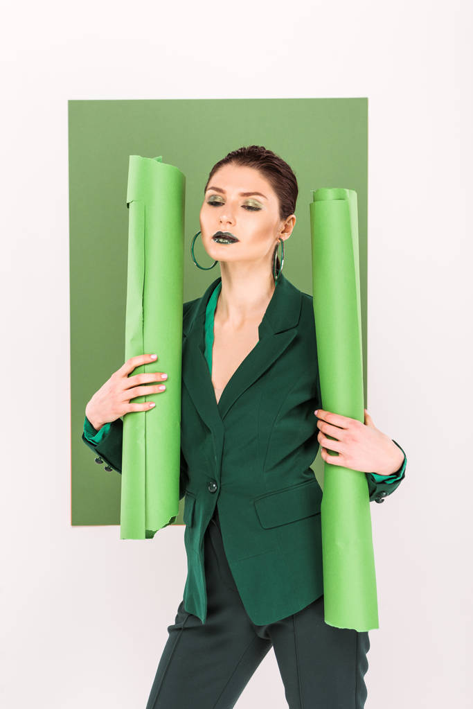 piękny stylowy kobieta trzymając rolki papieru i pozowanie z widokiem na zielony na tle - Zdjęcie, obraz