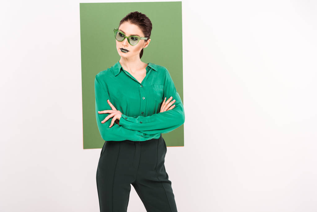 hermosa mujer de moda en gafas de sol posando y mirando hacia otro lado con verde marino en el fondo
 - Foto, Imagen