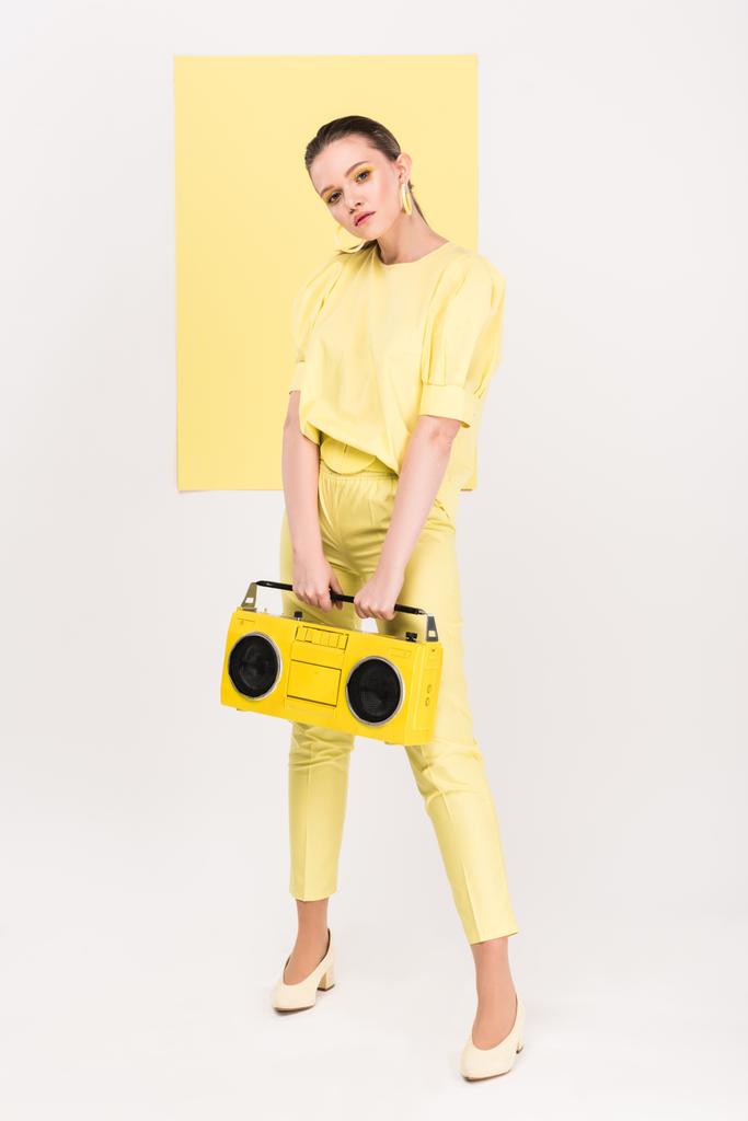 stylish girl holding retro boombox and posing with limelight on background - Photo, Image