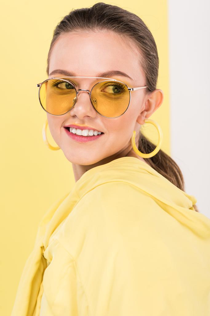 bela menina na moda em óculos de sol sorrindo e posando com ribalta no fundo
 - Foto, Imagem