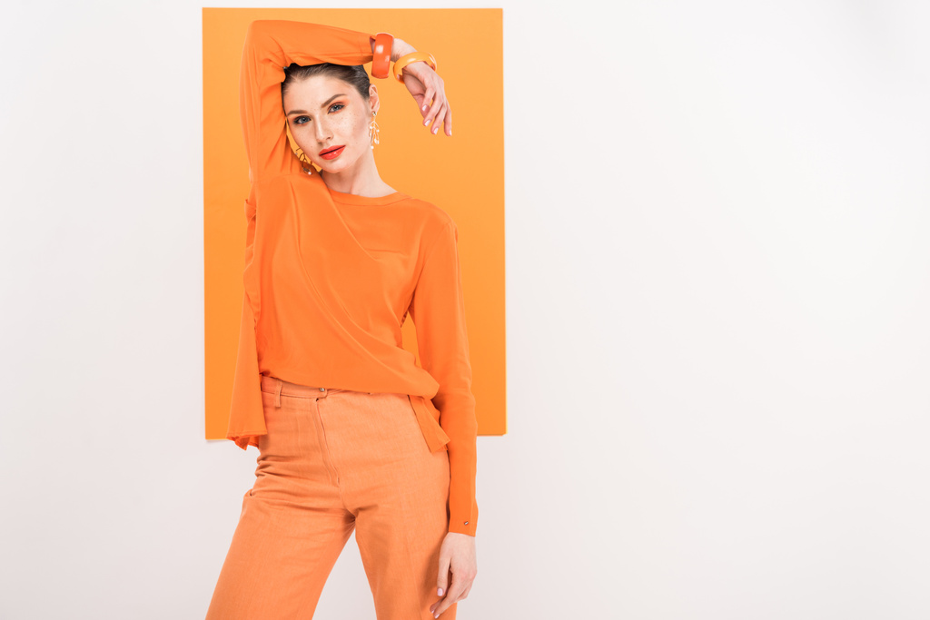 beautiful fashionable woman looking at camera and posing with turmeric on background - Photo, Image