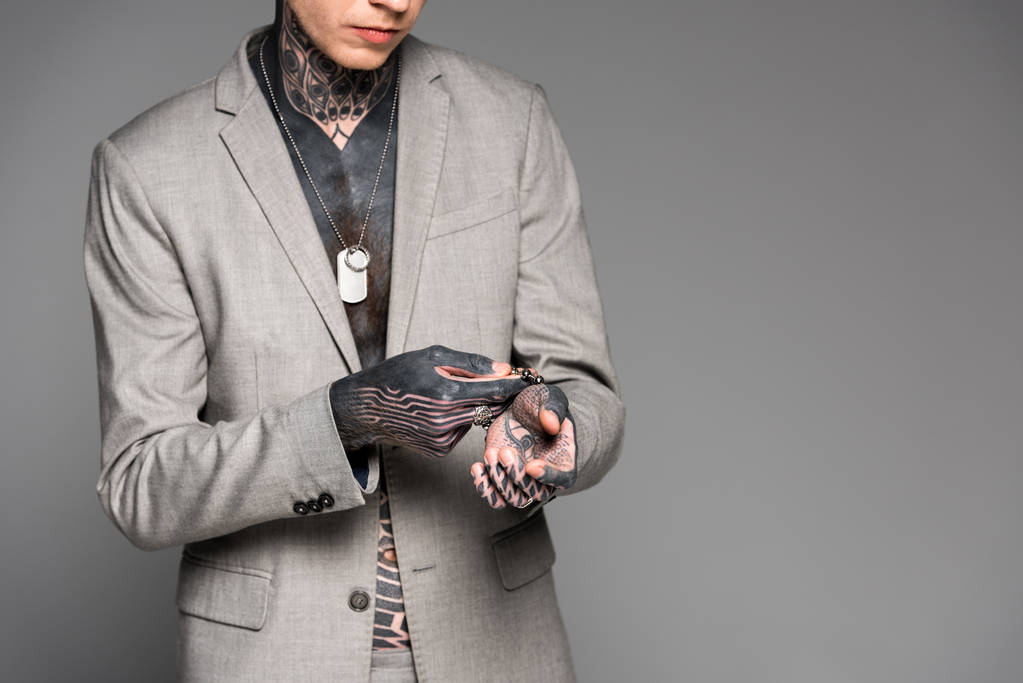 περικοπεί shot κομψό τατουάζ άνθρωπος προσαρμογή βραχιόλι που απομονώνονται σε γκρι - Φωτογραφία, εικόνα