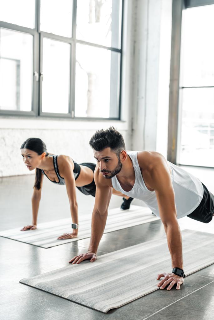 atletico giovane uomo e donna in abbigliamento sportivo facendo flessioni su stuoie di yoga in palestra
  - Foto, immagini