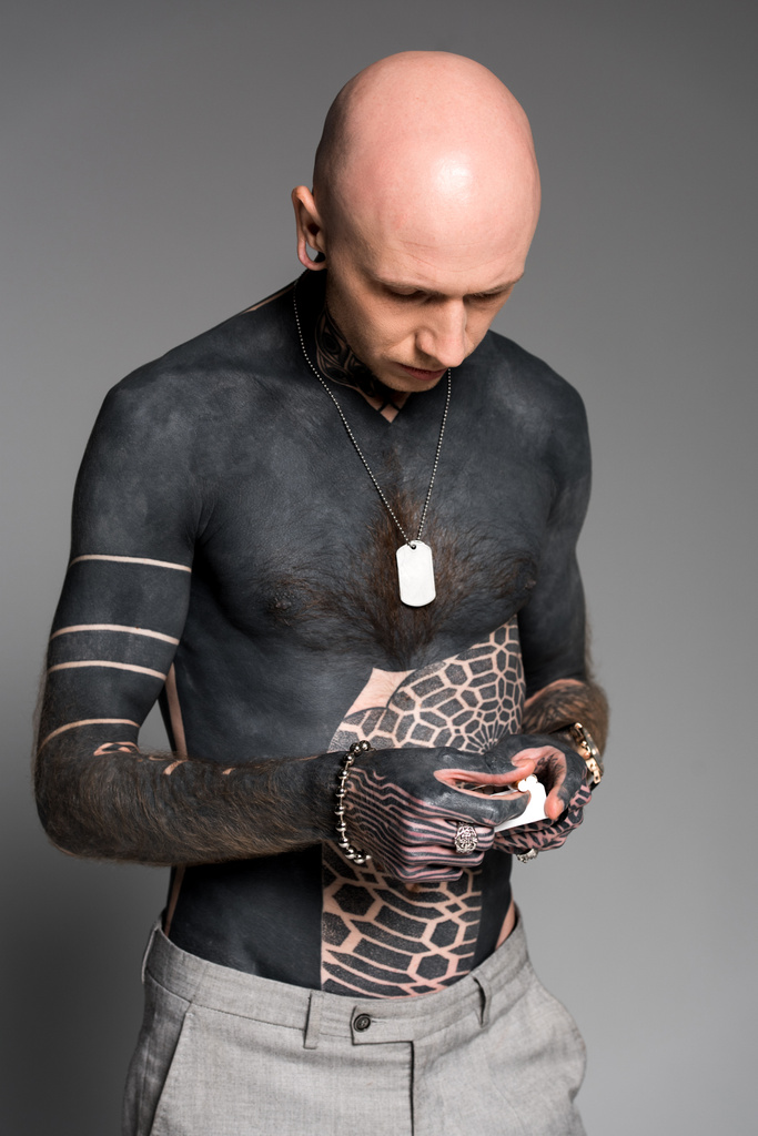 голый мужчина с татуировками с коробкой сигарет, изолированной на сером
 - Фото, изображение