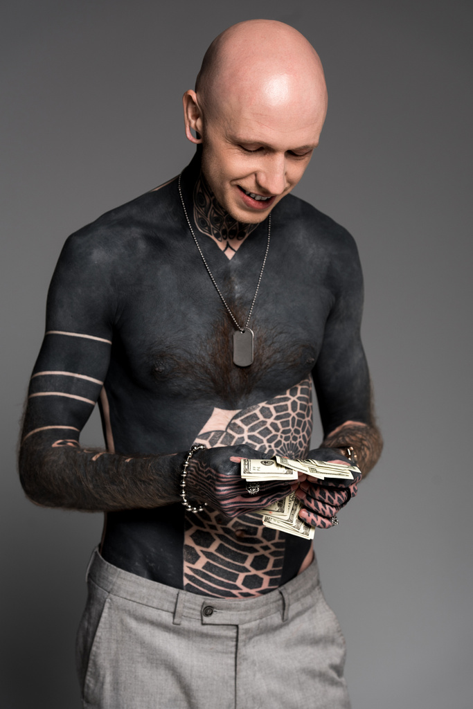 homme tatoué torse nu et souriant comptant les billets en dollars isolés sur gris
 - Photo, image