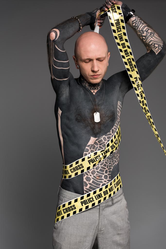 лисий без сорочки татуйований чоловік, обгорнувшись поперечною лінією, ізольований на сірому
 - Фото, зображення