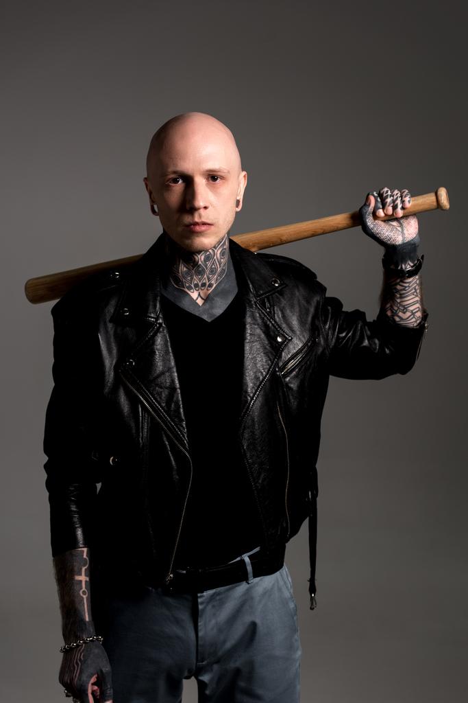 cool tatoué homme en cuir veste tenant batte de baseball sur les épaules et regardant caméra isolé sur gris
 - Photo, image