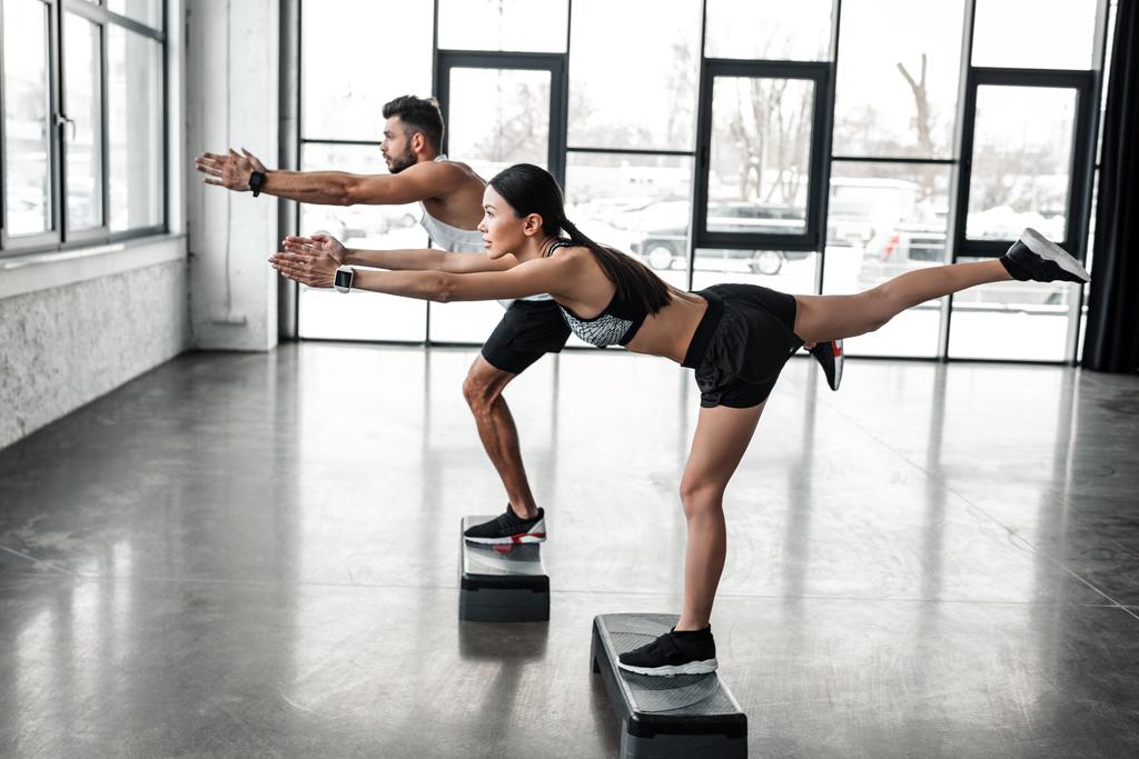 вид збоку спортивного молодого чоловіка і жінки в спортивному одязі вправи з кроковими платформами в спортзалі
 - Фото, зображення