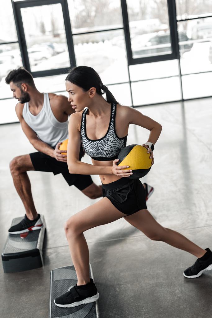 sportovní mladý pár v sportovní výcvik s krokem platformy v tělocvičně - Fotografie, Obrázek