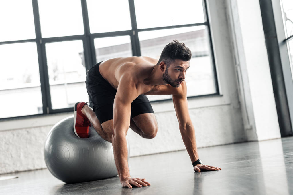 joven deportista con el pecho desnudo haciendo ejercicio en la pelota de fitness en el gimnasio
 - Foto, imagen