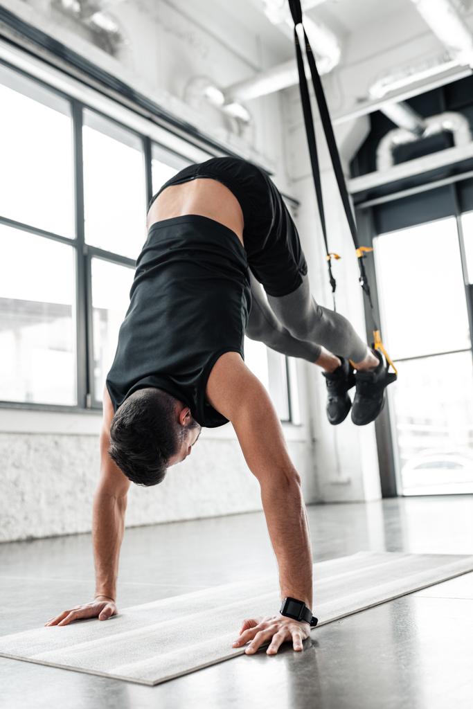 jeune sportif exécutant handstand sur tapis de yoga et l'entraînement avec des bandes de résistance dans la salle de gym
 - Photo, image