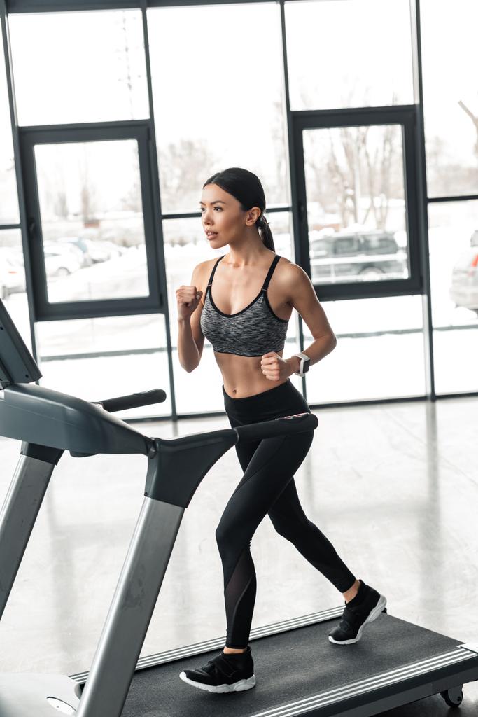 beautiful young sportswoman running on treadmill in gym  - Photo, Image