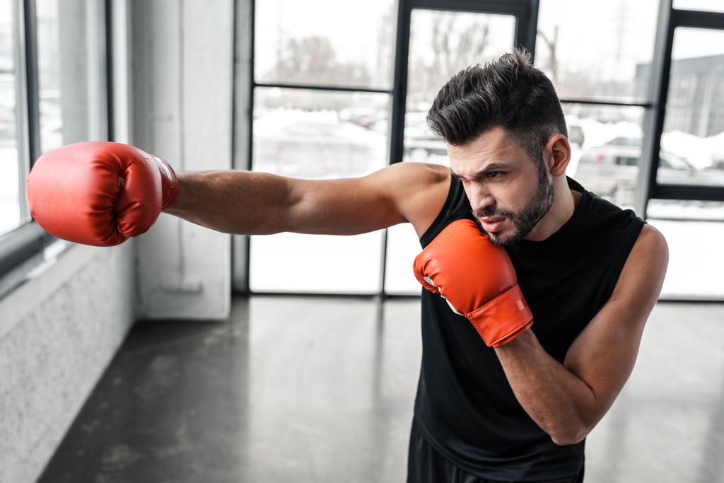 schöner sportlicher junger Mann in Boxhandschuhen beim Training im Fitnessstudio  - Foto, Bild