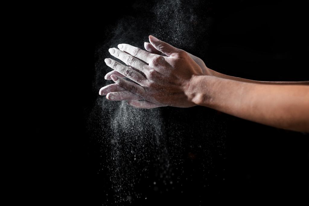 close-up partial view of sportswoman applying talcum powder on hands isolated on black - Photo, Image