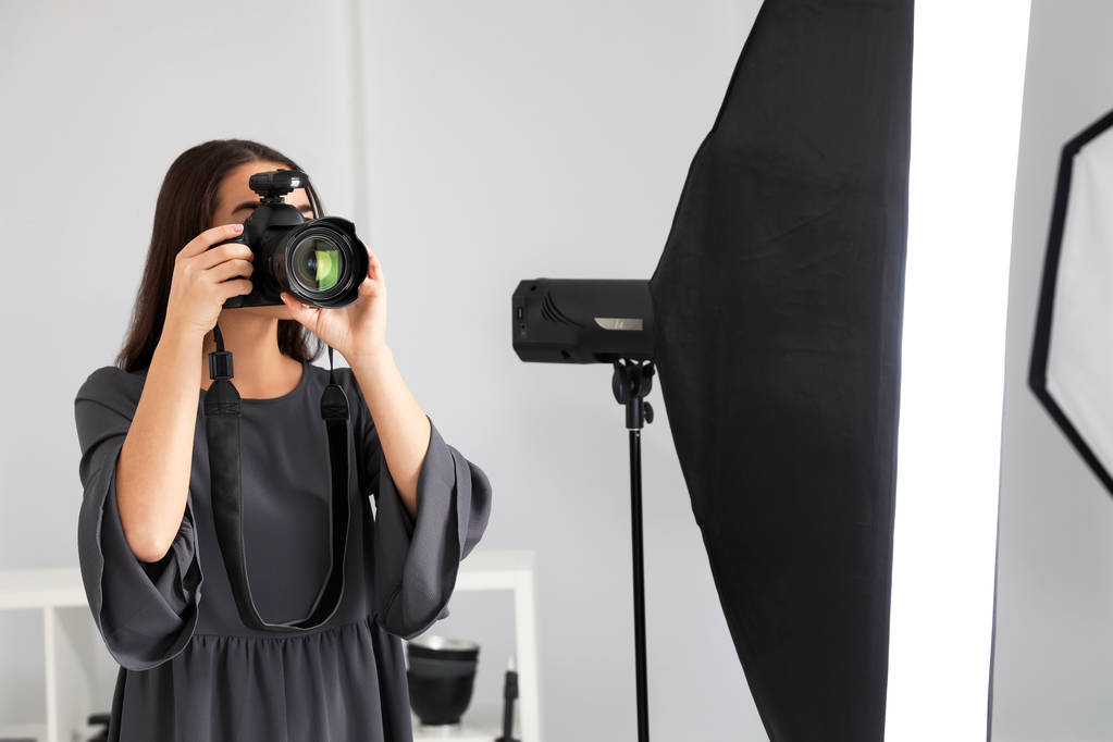 junge Frau mit professioneller Kamera im Fotostudio - Foto, Bild