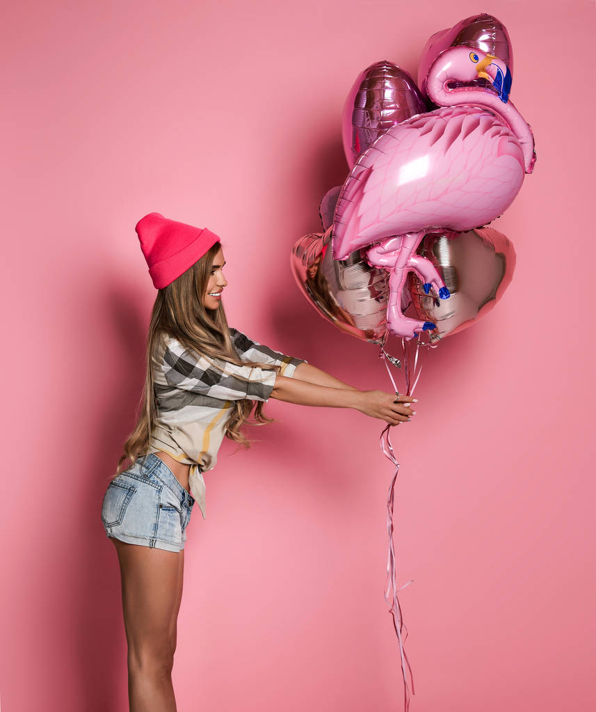 mooie vrolijke meisje houdt een stelletje roze ballonnen op een roze pastel achtergrond. - Foto, afbeelding