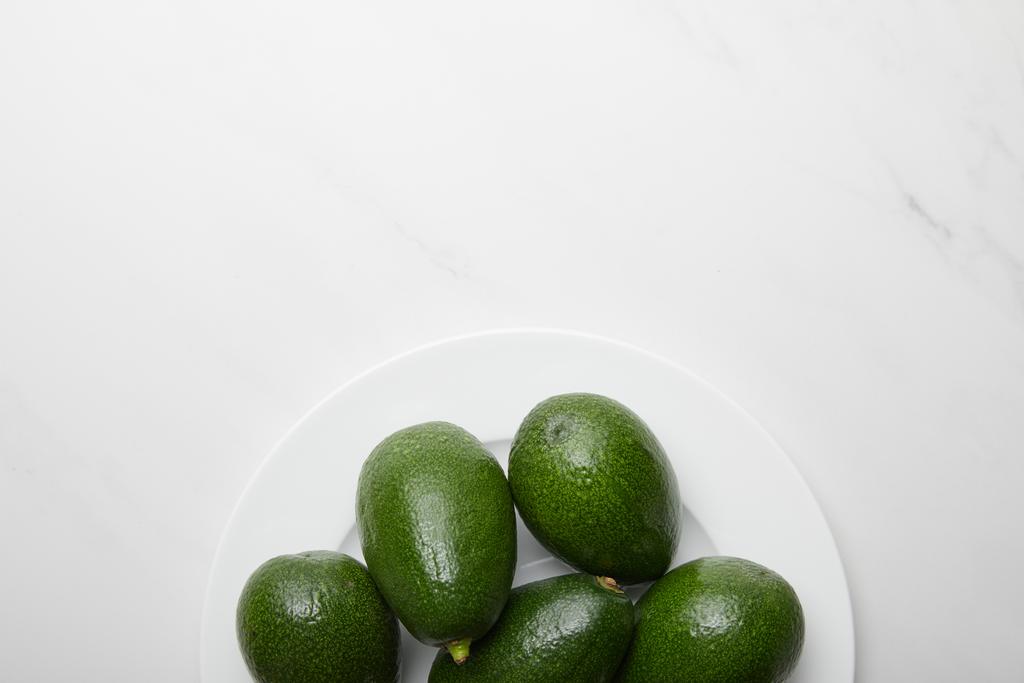 Ansicht von Avocados im Teller auf grauem strukturiertem Hintergrund - Foto, Bild