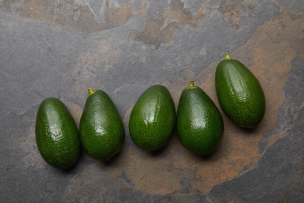bovenaanzicht van avocado's over de grijze achtergrond - Foto, afbeelding