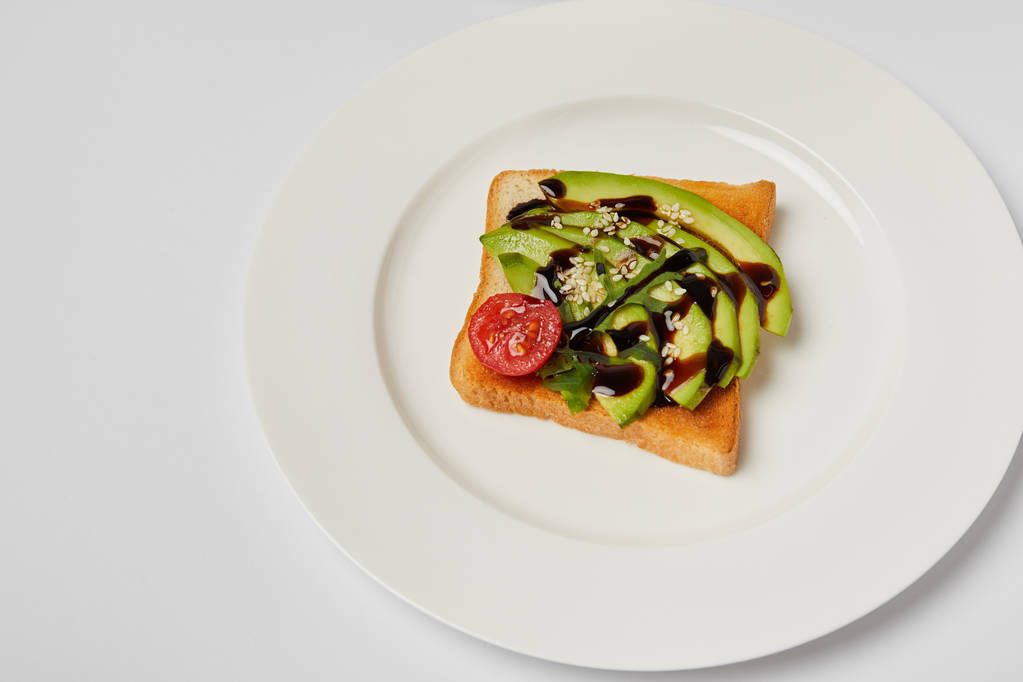 Draufsicht auf Toast mit Avocado und Kirschtomate auf grauem Hintergrund - Foto, Bild