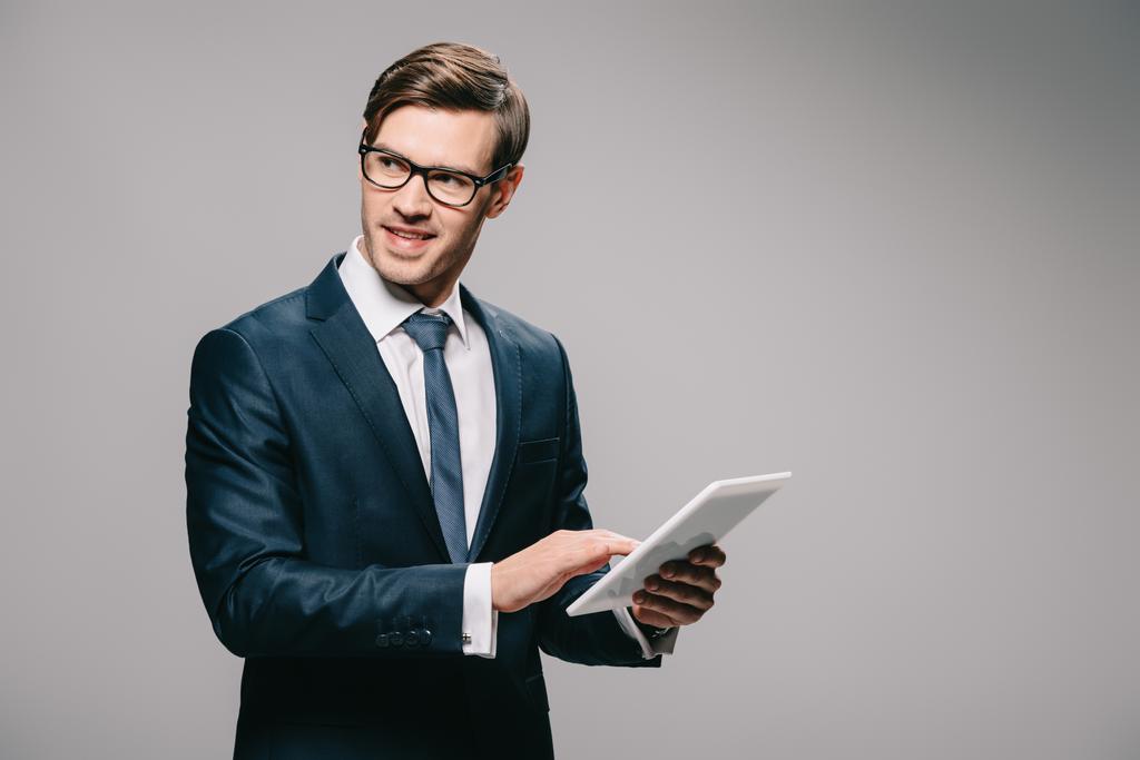 cheerful businessman in glasses using digital tablet isolated on grey  - Photo, Image
