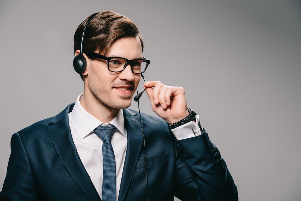homem bonito em óculos usando fone de ouvido e segurando microfone no fundo cinza
  - Foto, Imagem