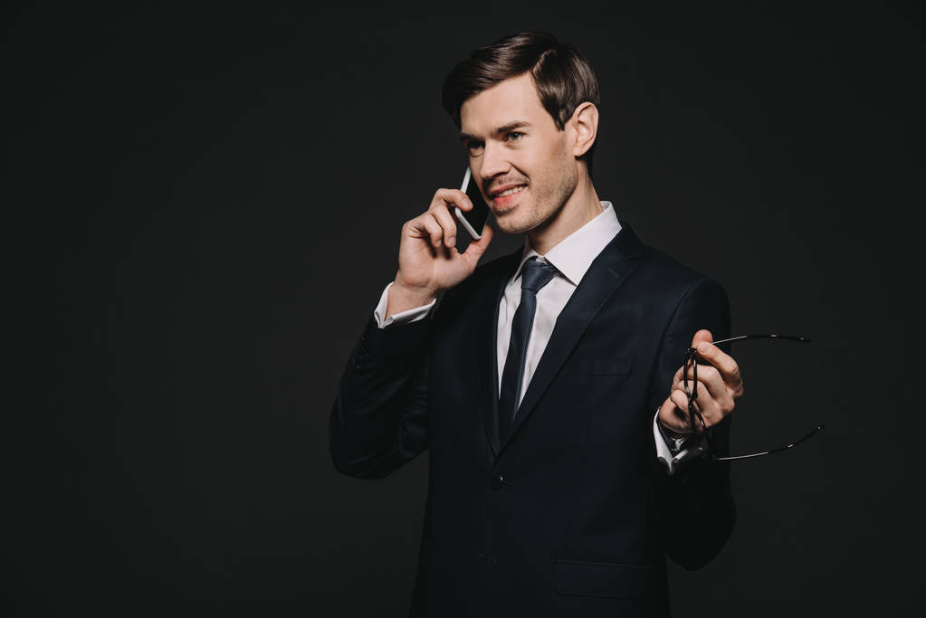 alegre hombre de negocios hablando en smartphone aislado en negro
 - Foto, Imagen