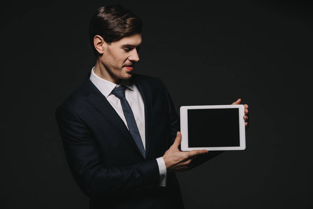 黒に分離された空白の画面とデジタル タブレットを保持している陽気なビジネスマン - 写真・画像