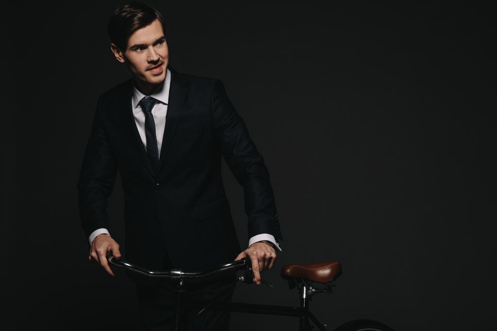 allegro uomo d'affari in tuta tenendo bicicletta isolata su nero
 - Foto, immagini