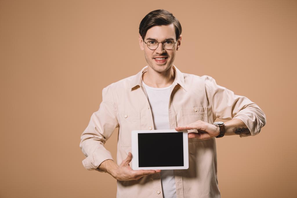 Glimlachende man in glazen houden digitale tablet met leeg scherm geïsoleerd op beige  - Foto, afbeelding