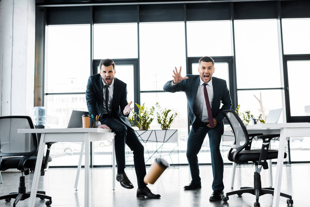hombres de negocios emocionales mirando la caída de la taza de papel en la oficina moderna
  - Foto, imagen