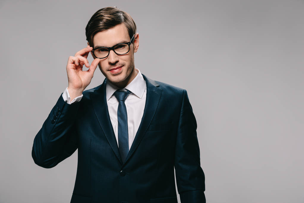 hombre de negocios serio tocando gafas aisladas en gris
 - Foto, Imagen