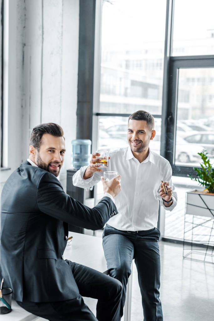 homens de negócios sorridentes brindam com copos de uísque
  - Foto, Imagem