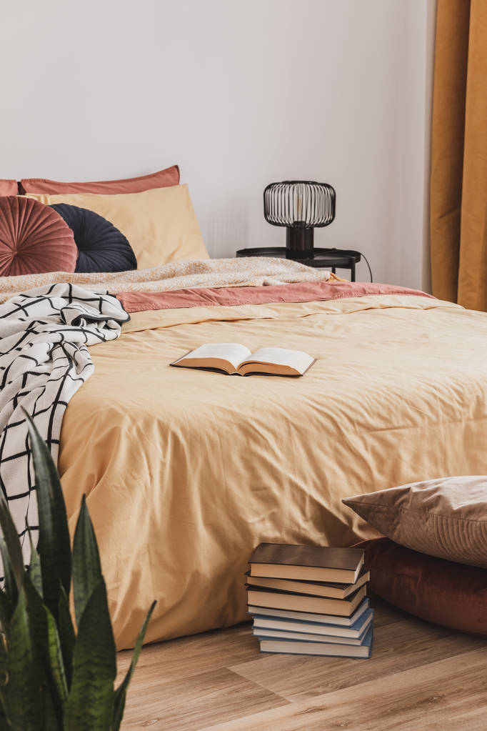 Mucchio di libri in piedi di letto king size con piumone giallo e cuscini zenzero
 - Foto, immagini