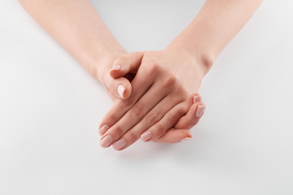 Vista parcial de las manos apretadas femeninas sobre fondo blanco
  - Foto, imagen