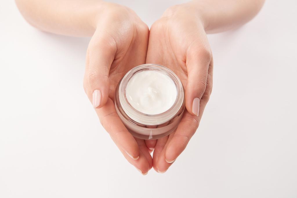 Gedeeltelijke weergave van vrouw cosmetische crème toe te passen op witte achtergrond - Foto, afbeelding