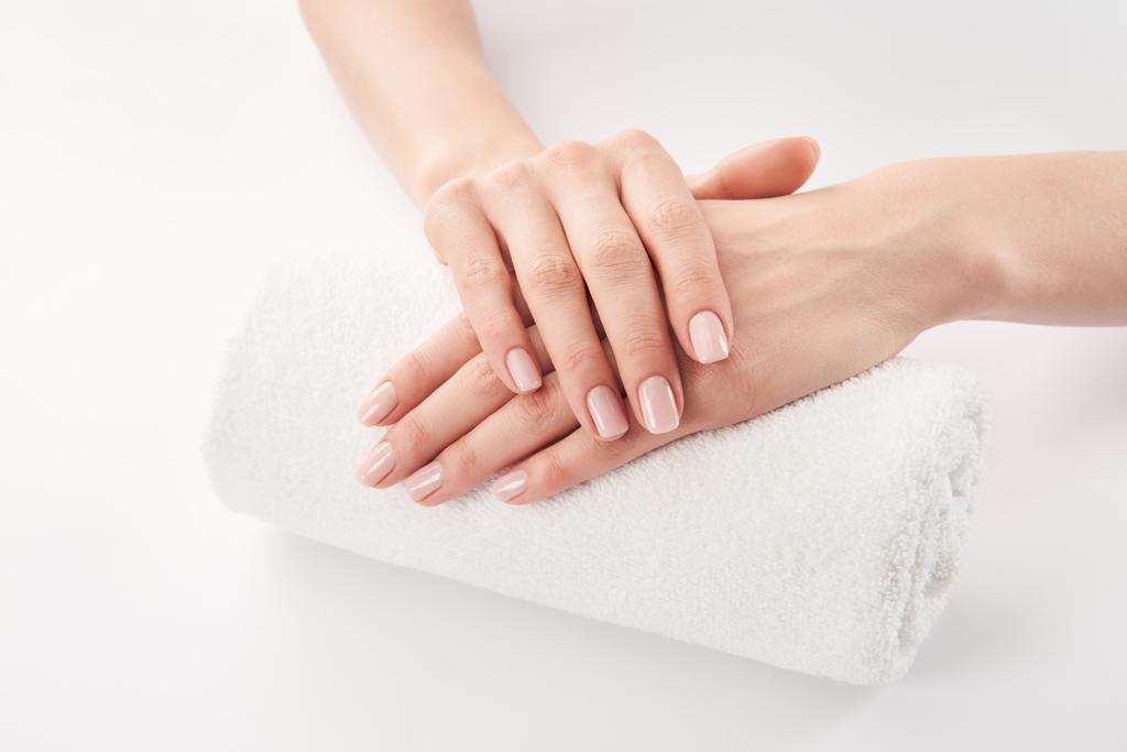 Vista parcial de las manos femeninas sobre rizo suave toalla enrollada sobre fondo blanco
 - Foto, imagen