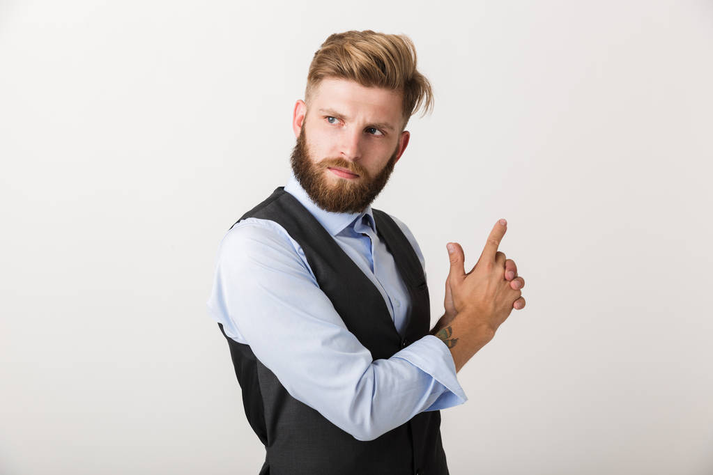 Confident young business man standing isolated over white background, pointing at copy space - Photo, Image
