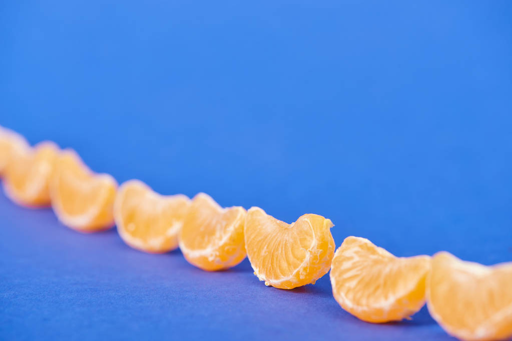 селективный фокус очищенных кусочков мандарина на синем фоне
 - Фото, изображение