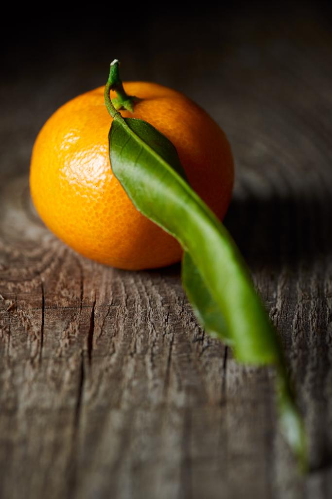 селективный фокус сочного мандарина с зеленым листом на деревянном столе
  - Фото, изображение