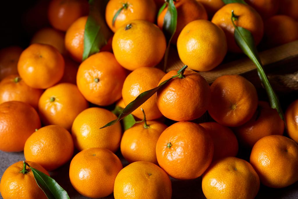 selectieve aandacht van zoete mandarijnen met groene bladeren - Foto, afbeelding