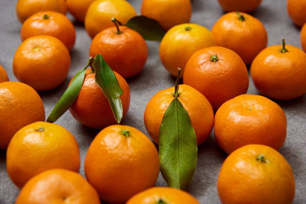 selective focus of orange tangerines with green leaves on grey table - Photo, Image