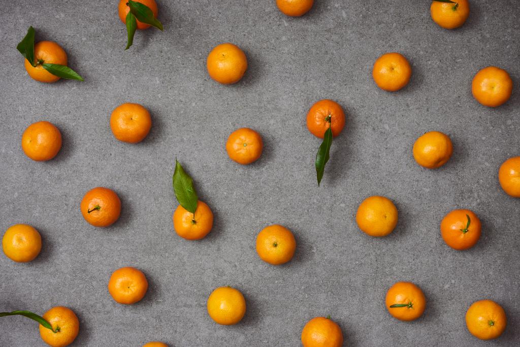 płaskie ukształtowanie słodkiej mandarynki z zielonych liści na stół szary - Zdjęcie, obraz