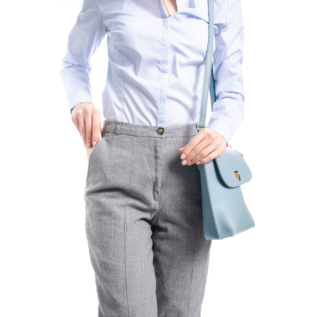 Žena v šedé kalhoty a modrý modrou košili pytel dát smartphone v kapse makra - Fotografie, Obrázek