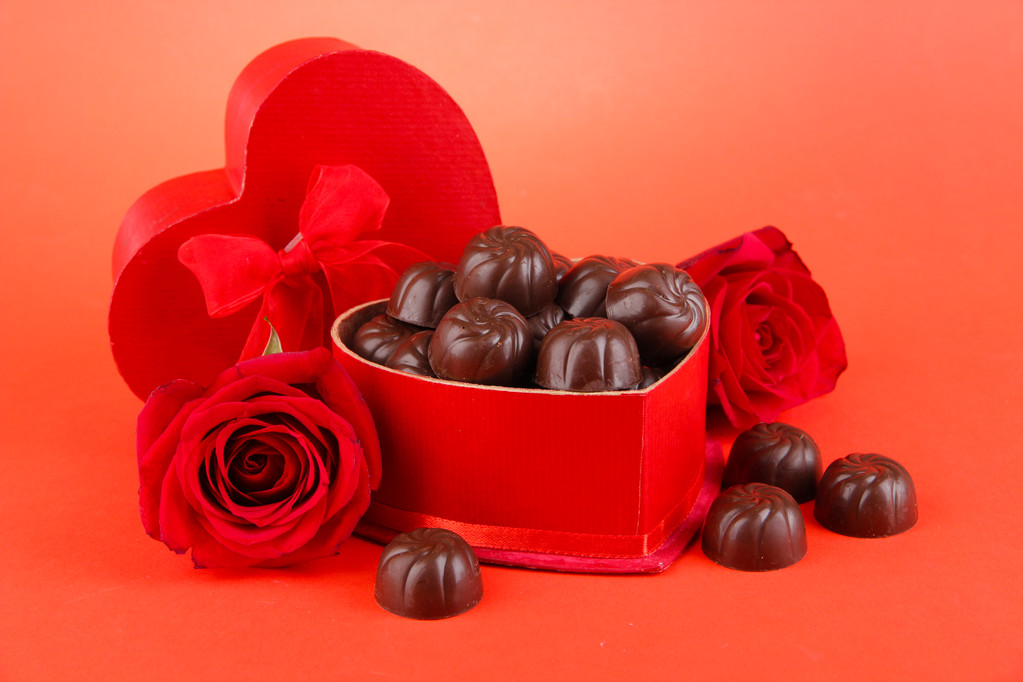 Шоколадные конфеты в подарочной коробке на красном фоне
 - Фото, изображение