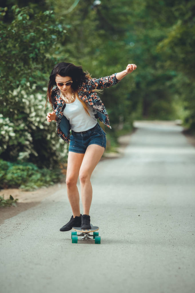 молода красива підходить жінка на скейтборді в парку
 - Фото, зображення
