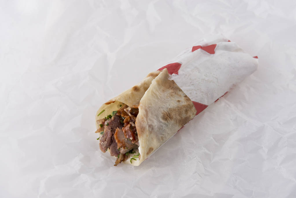 Sabroso sándwich de shawarma sobre fondo de papel blanco
 - Foto, Imagen