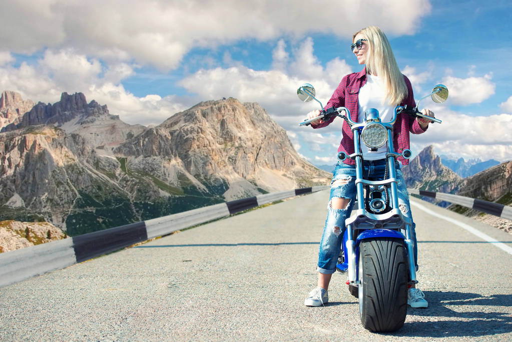 Chica ciclista montando una moto a lo largo de la carretera de montaña
. - Foto, Imagen